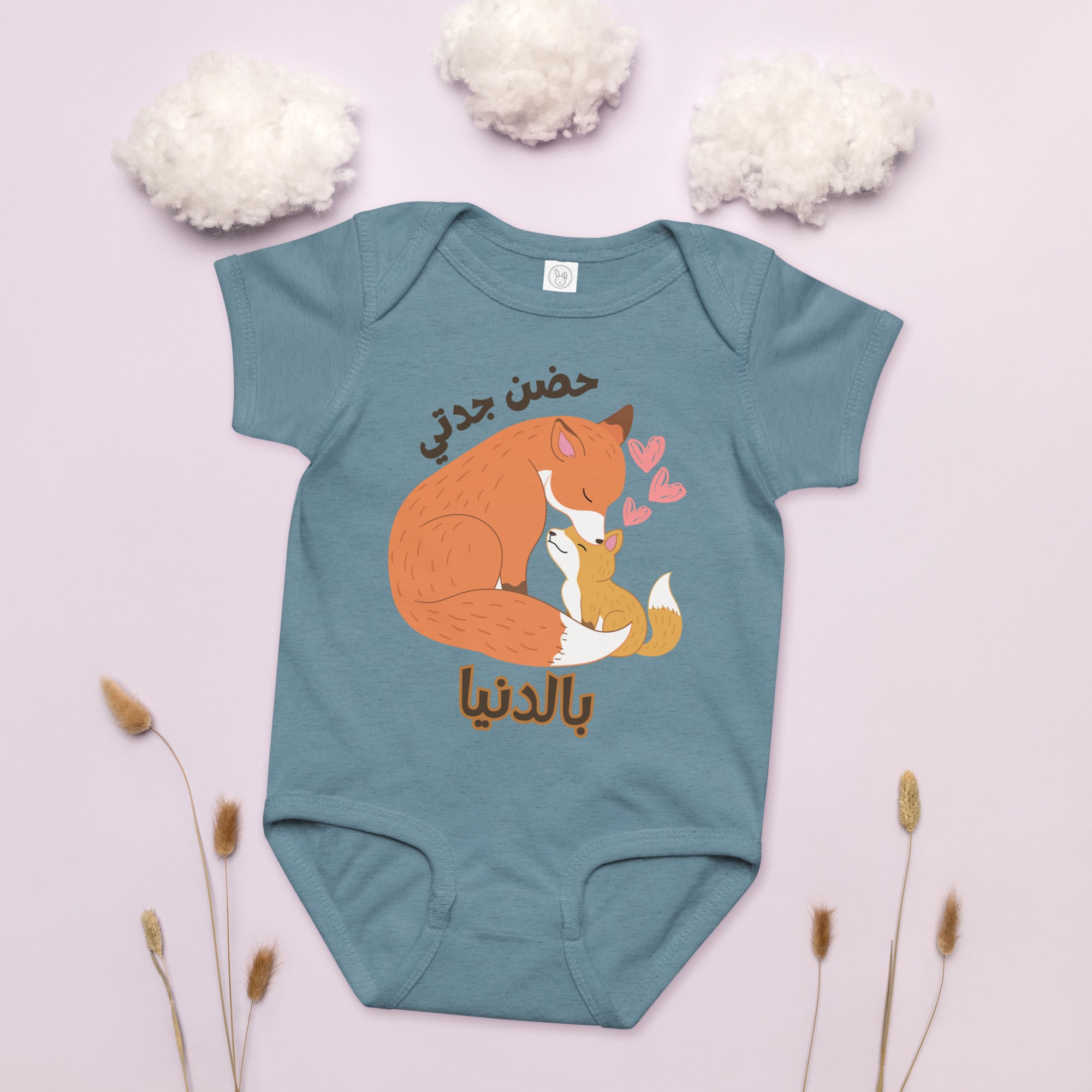 Grandma and baby foxes with hearts of love surrounding them. Arabic text that says Grandma hugs mean the world.